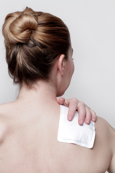 Heat plasters provide pain relief with proper use Woman using a heat plaster for pain relief in the shoulder