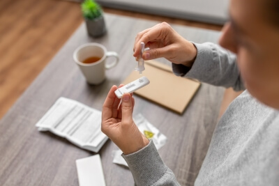 A woman performing a medical rapid test at home on a table