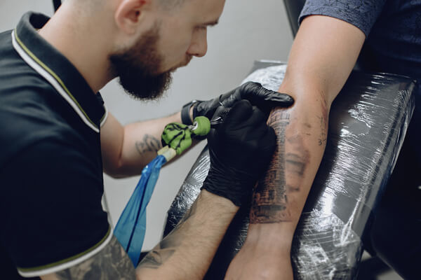 Tattoo artist wearing black nitrile gloves