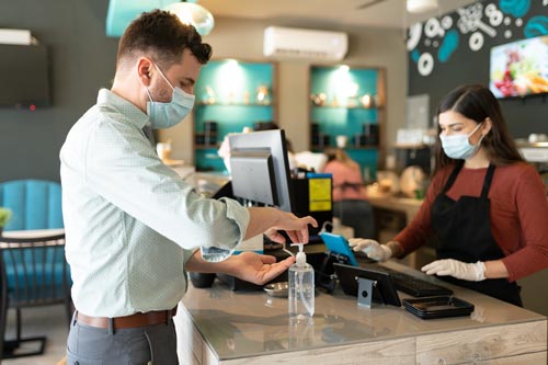 Man using skin disinfectant in a café